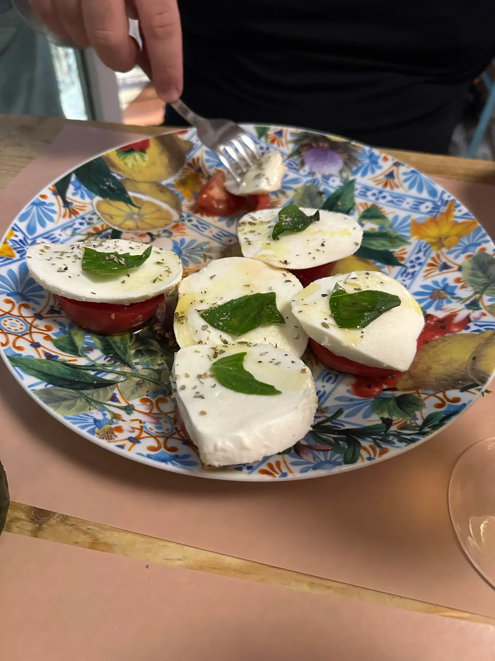 A plate of sliced tomato and mozzarella with basil