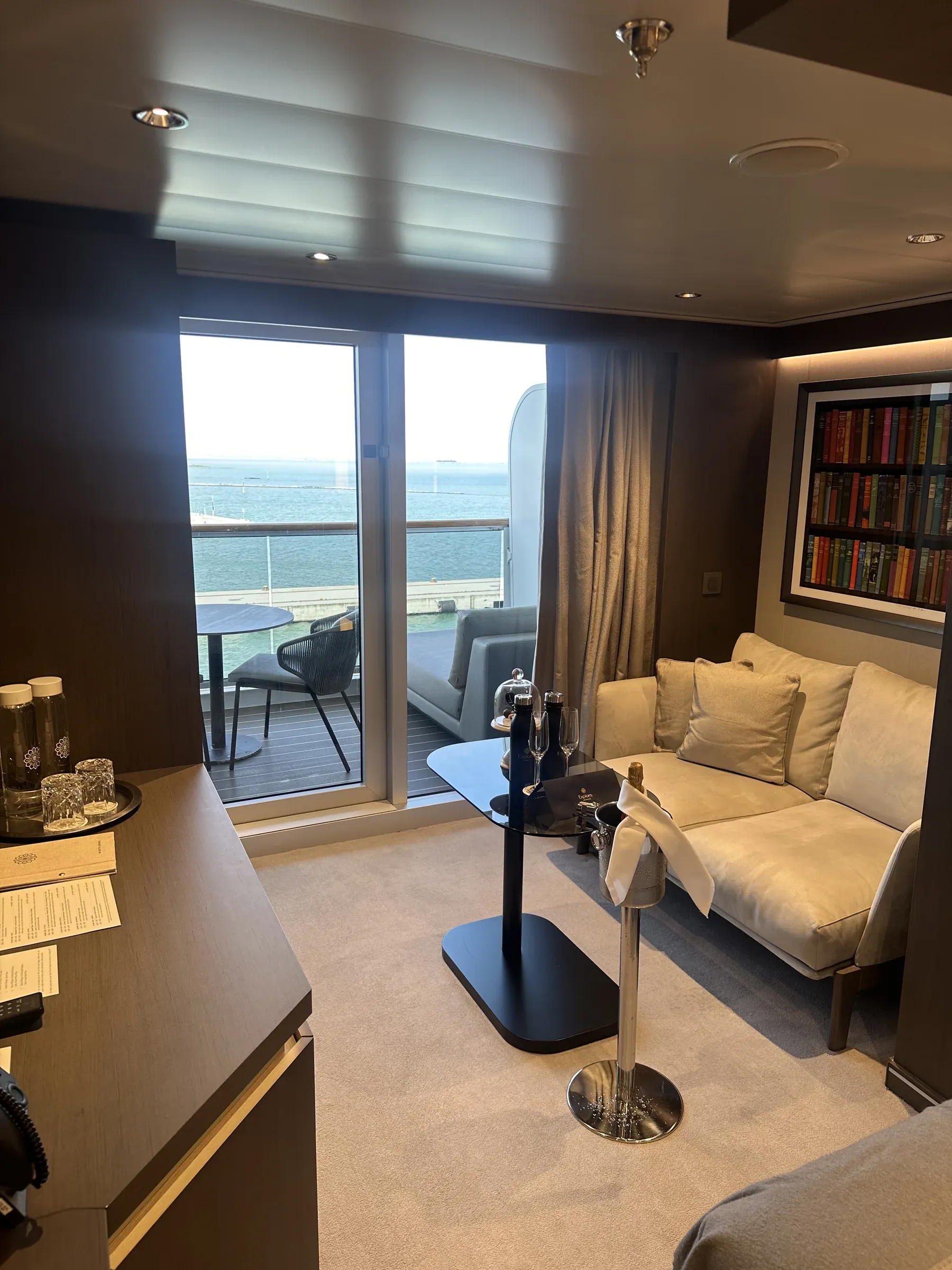 The living room of my suite aboard Explora I, a sofa and the terrace doors open to the sea