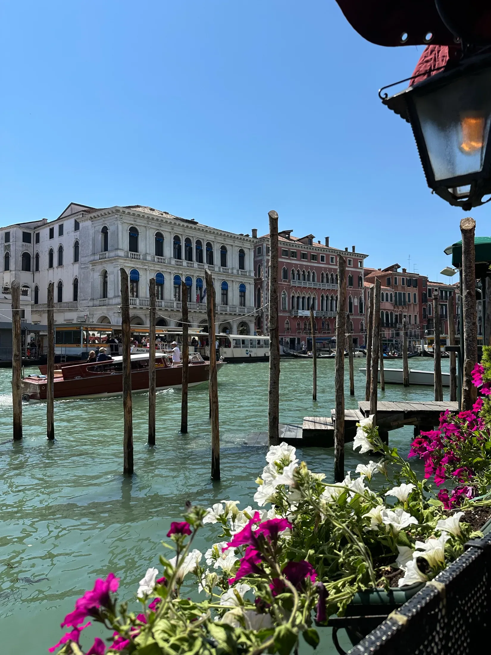 A Venice side canal with palazzi, boats, and flower boxes in the foreground